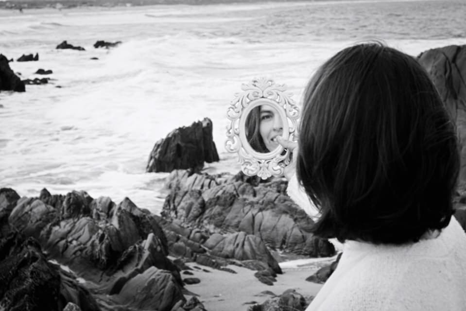 Caroluz mirándose en un espejo frente al mar